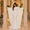 Angie Style Boutique off-white long-sleeve maxi dress with draped side cape panels on a model in a formal hallway