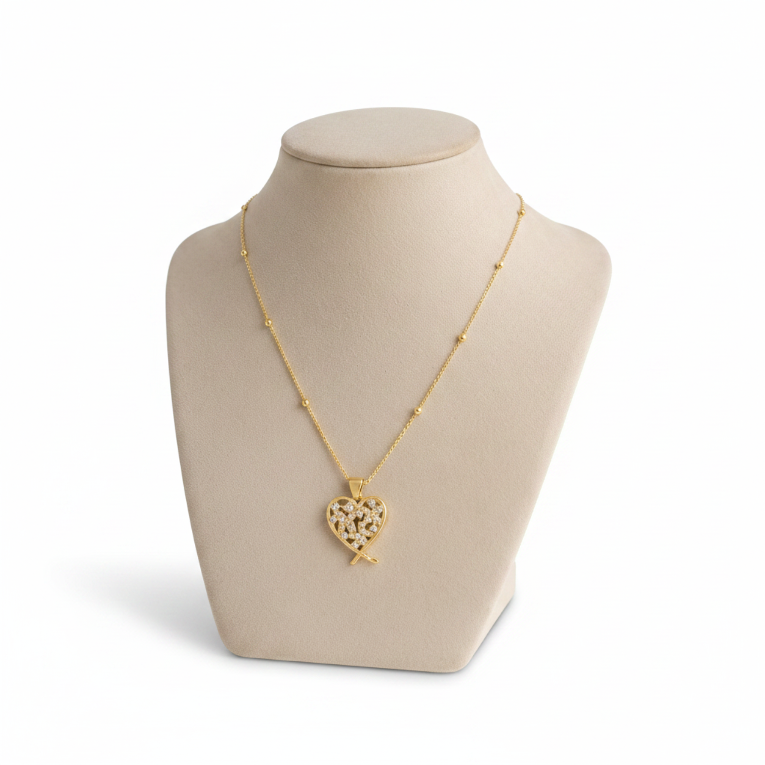 Angie Style Boutique gold heart pendant necklace with pavé cubic zirconia stones on a beige jewelry display bust