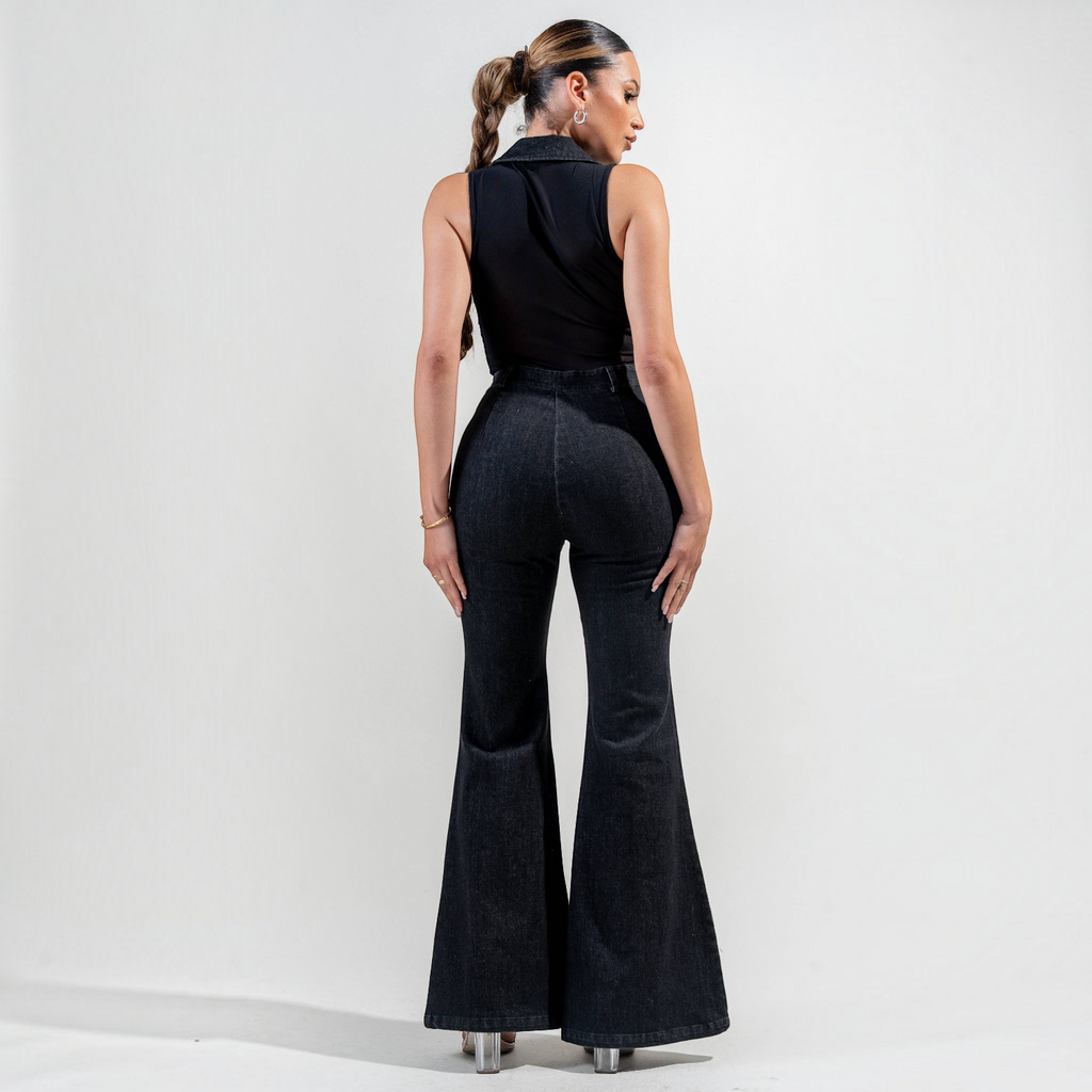 Model wearing an Angie Style Boutique black stretch washed denim and mesh jumpsuit with a flared leg, back view.